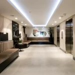 Lower lobby with cove lighting, wall coverings, and built-in couches at Costa Brava