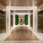 Wide view of the elevator lobby at the Rony Palace featuring accent lighting live moss wall and abstract wood sculpture renovated by Capital Contractor Services